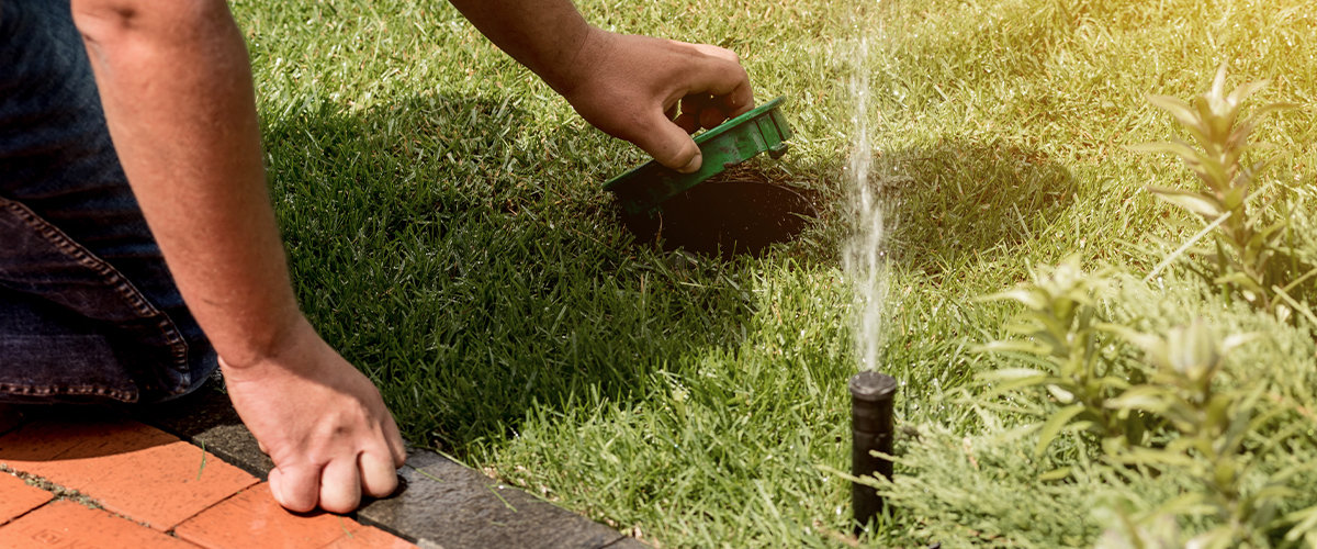 Man doing sprinkler maintenance in backyard